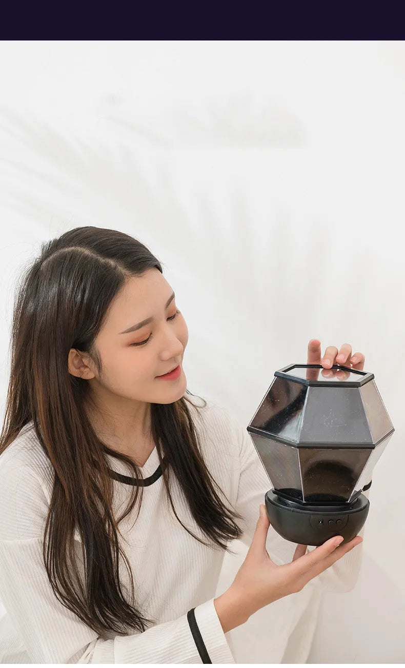 Battery-powered children's rotating star night light projector showing LED colours on a ceiling.