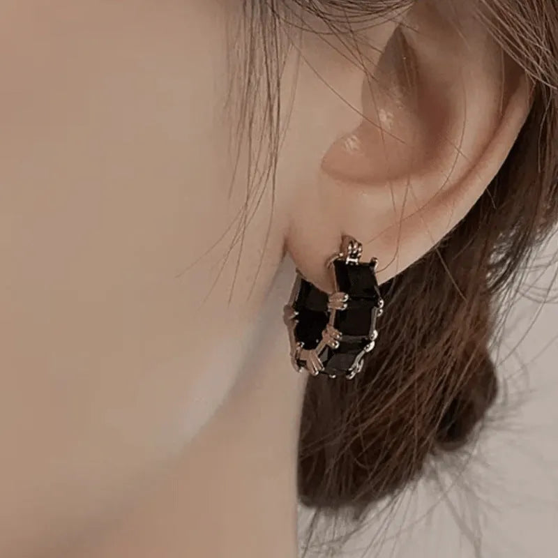 Geometric U-shaped gold tone earring with a round black zircon stone.