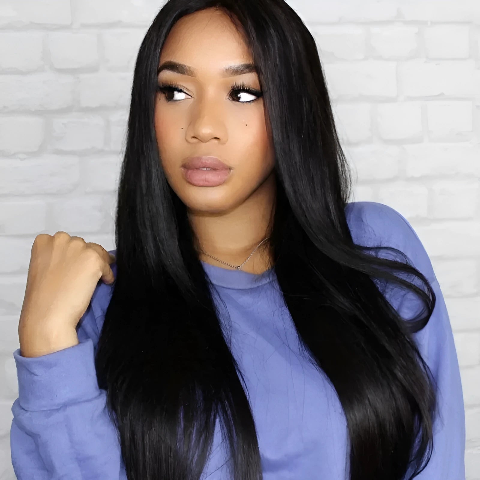 A woman wearing a long straight black synthetic wig with a centre-parted fringe.