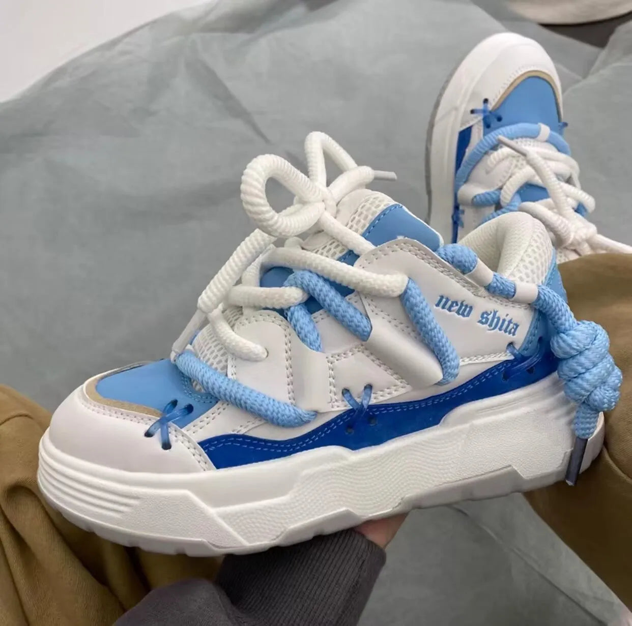 Grey women's chunky lace-up sneakers with a thick rubber sole and retro design on a white background.
