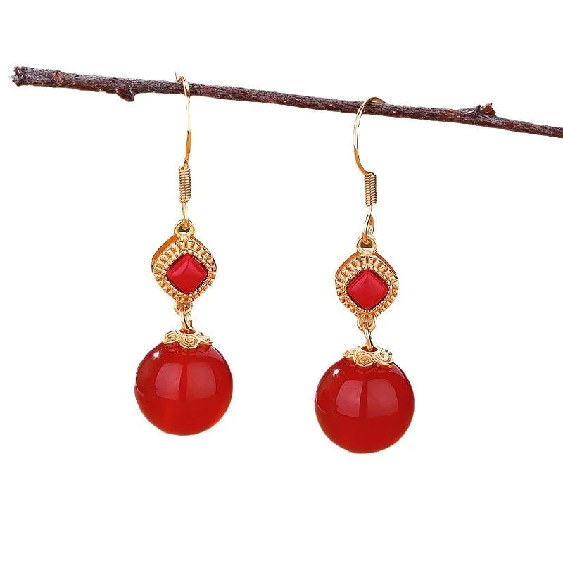 Round red agate bead drop earrings with silver-inlaid jasper accents on a geometric copper alloy hook.