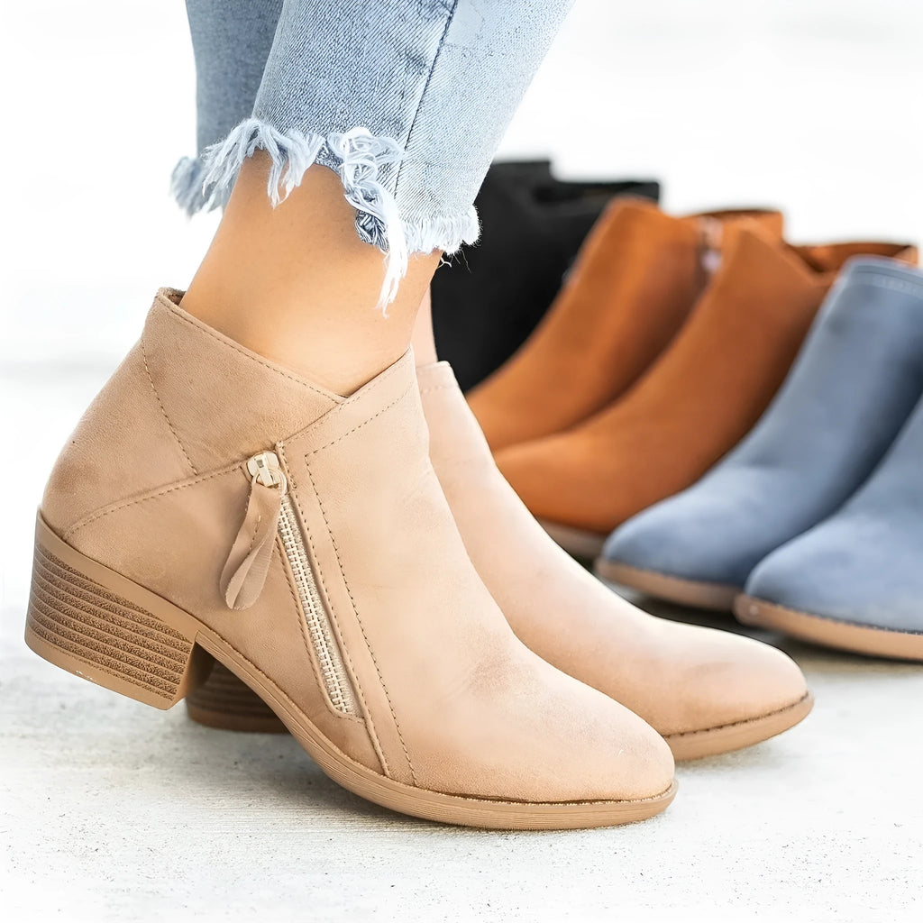 Blue suede Dr. Martens ankle boots with side zip and chunky heel on a white background.