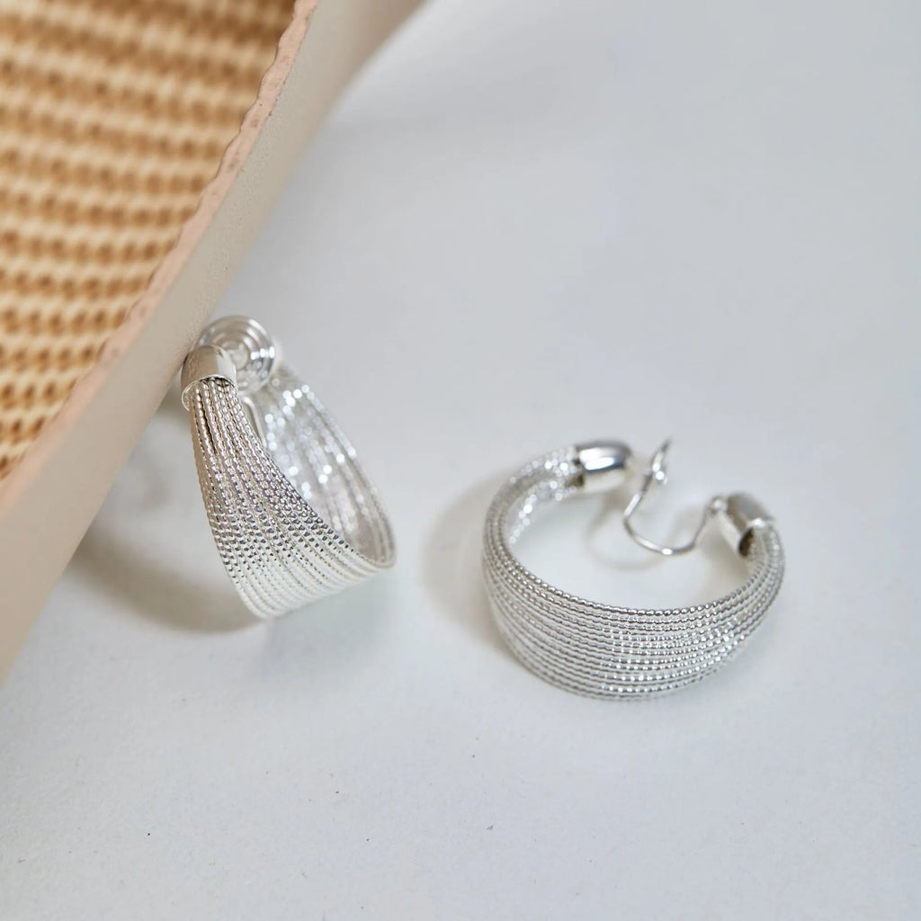 A pair of multi-layer geometric earrings in gold or silver electroplated finish, available as studs or clips.