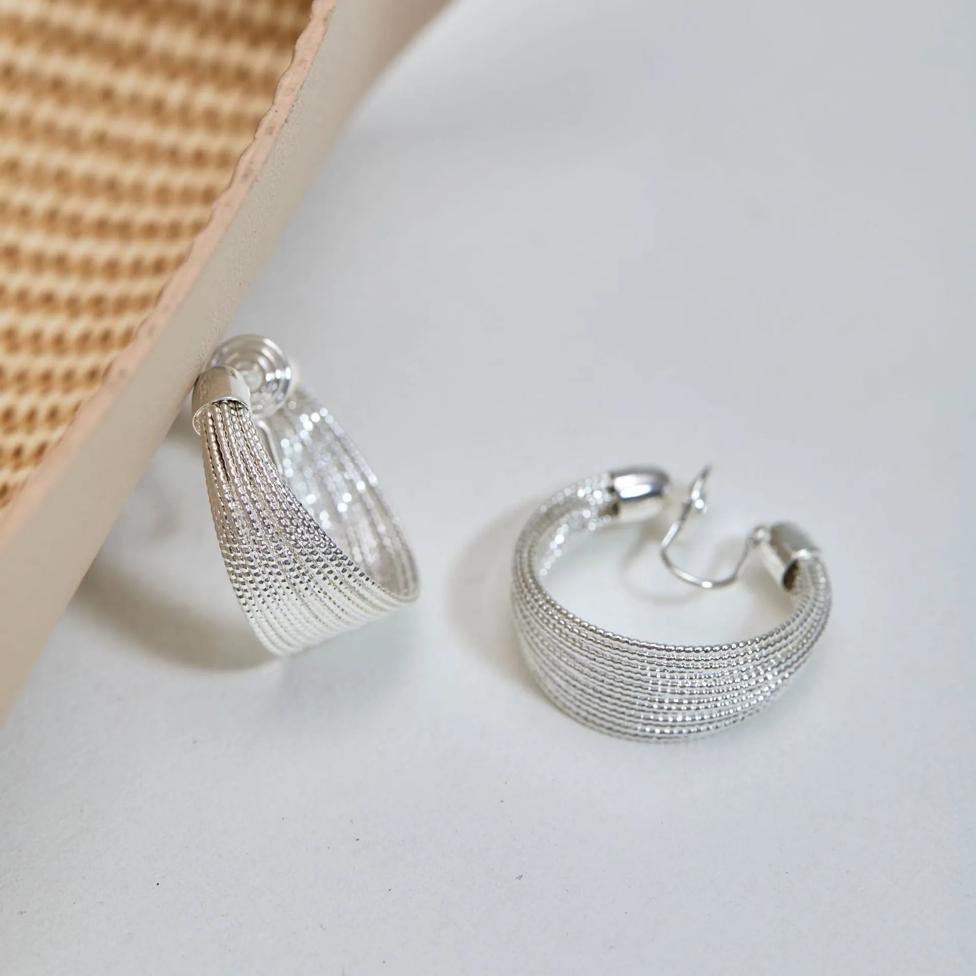 A pair of multi-layer geometric earrings in gold or silver electroplated finish, available as studs or clips.