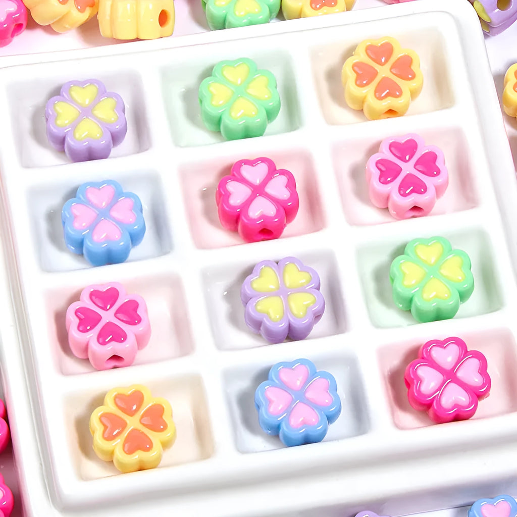 A selection of 15mm frosted acrylic beads in various colours, each showing a four-leaf clover love pattern.