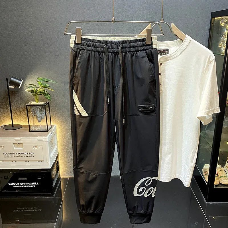 Men's solid black ultra-thin ice silk ankle-banded cropped casual trousers laid flat.