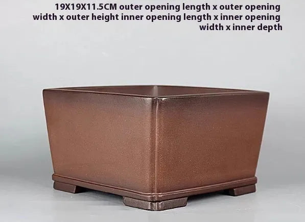 Handmade antique brown purple clay flower pot with classical design on a desktop.