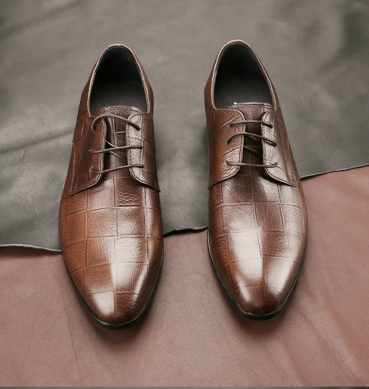 Men's black leather derby shoes with a pointed toe and rubber sole on a neutral background.