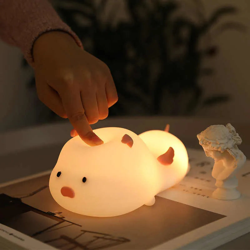Cute pig silicone night light in Pink with sleeping face design on a wooden table