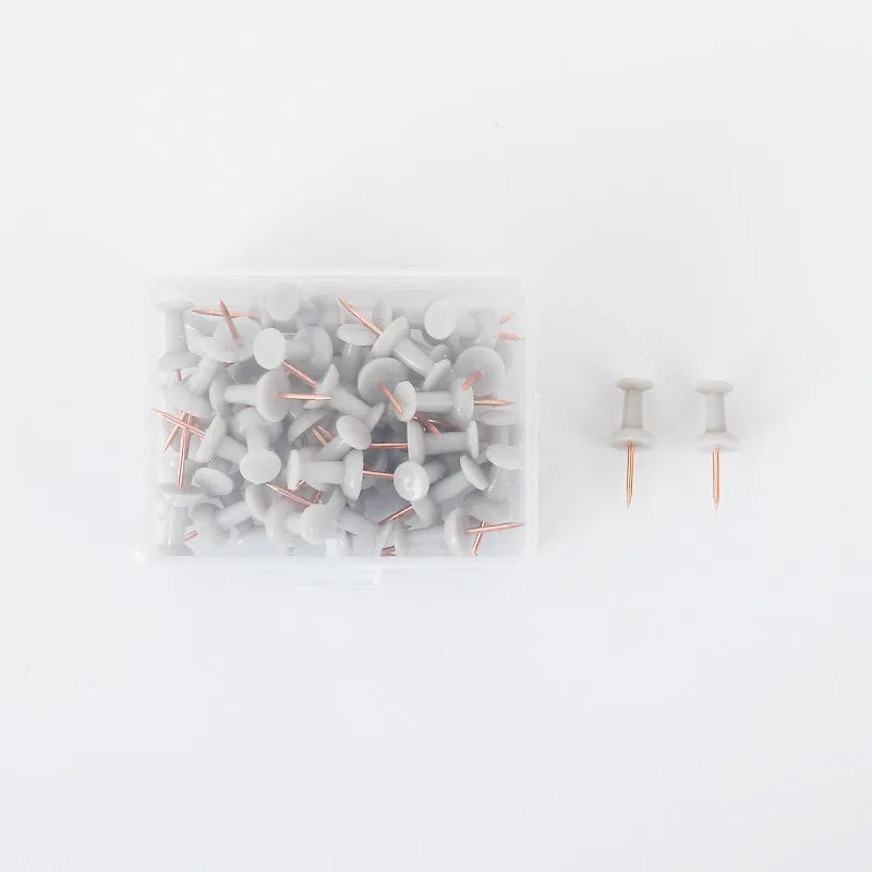 Set of 50 Morandi colour pushpins showing green, grey, and pink tones with different pin head styles on a corkboard.