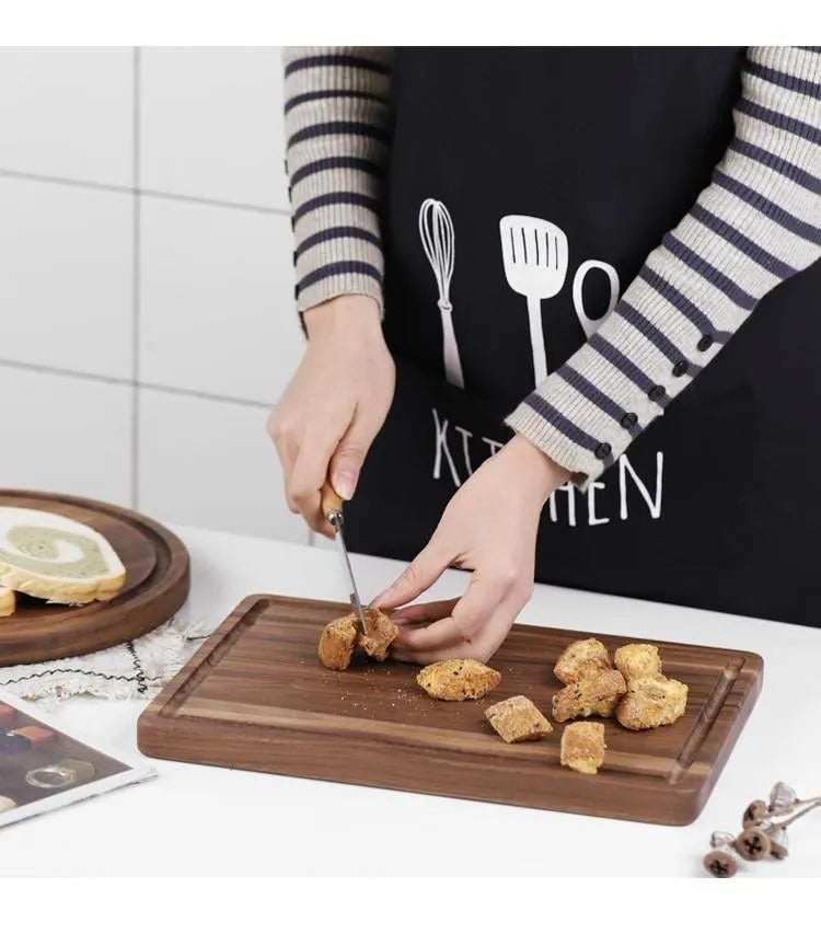 Solid black walnut wood cutting board with juice groove and side handle, shown in round and rectangular sizes.