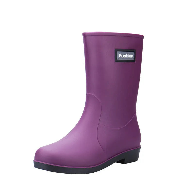 Women's black PVC mid-calf rain boots with a low heel on a wet surface.