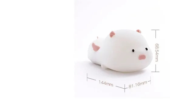 Cute pig silicone night light in Pink with sleeping face design on a wooden table