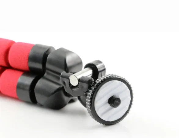 Black flexible octopus-style mini tripod with coiled legs next to a smartphone