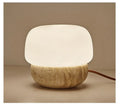 Cream-coloured retro style bedside lamp with a warm bulb on a table.