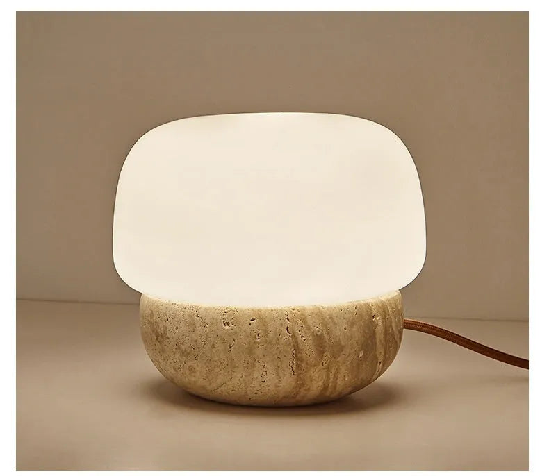 Cream-coloured retro style bedside lamp with a warm bulb on a table.