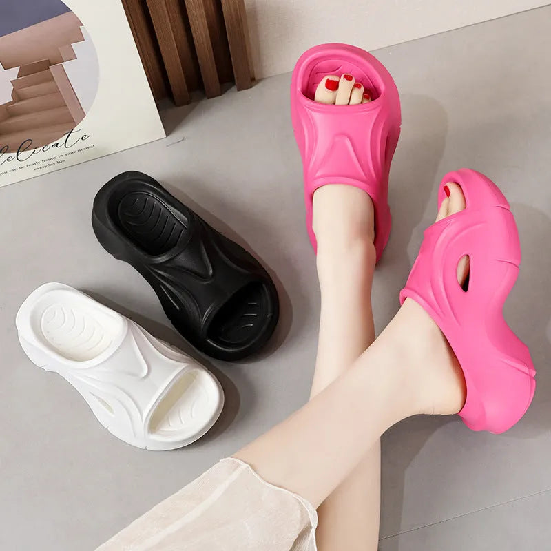 White women's EVA slippers with thick sole and round toe on a beach background.