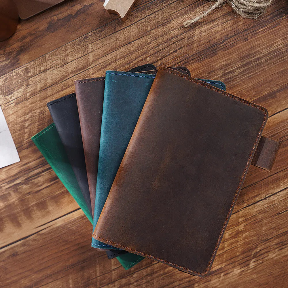 Handmade leather notebook in dark green, open on a desk showing wood-free paper pages.