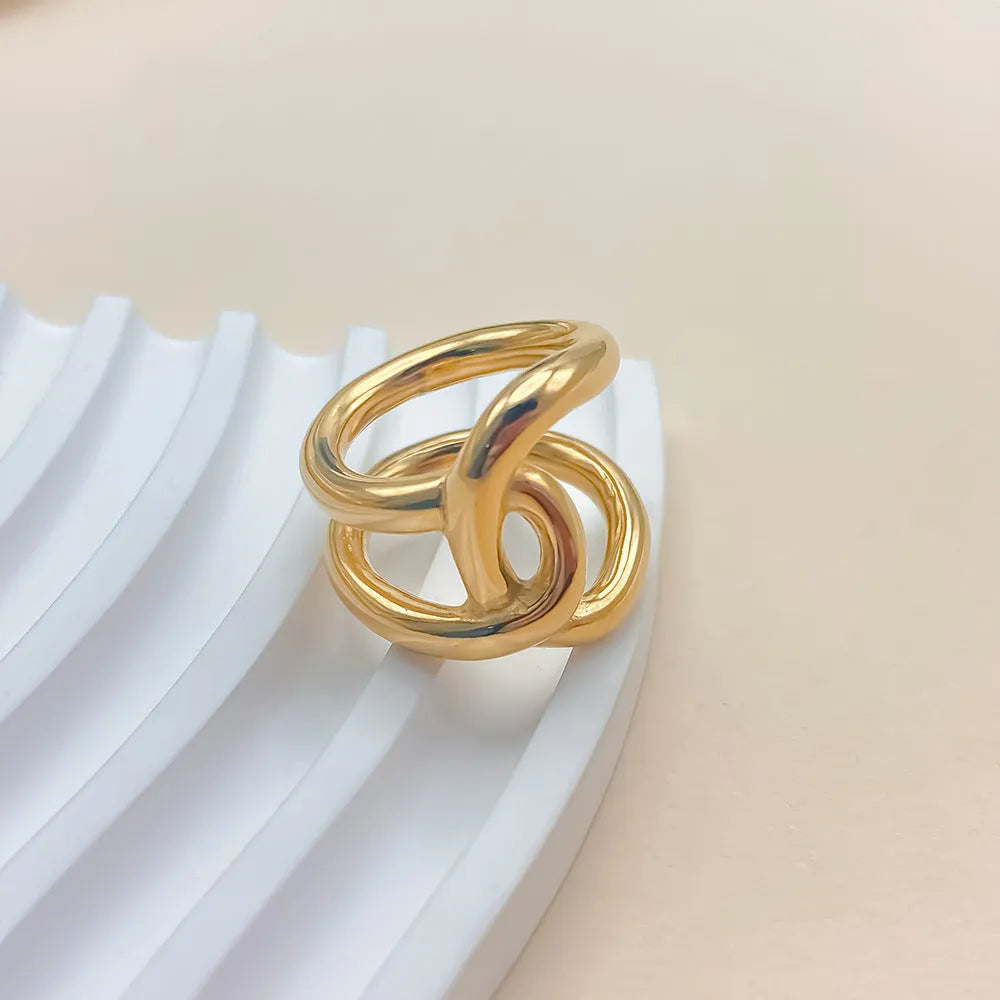 Women's stainless steel knotted geometric adjustable opening ring in gold or silver tone on a hand.