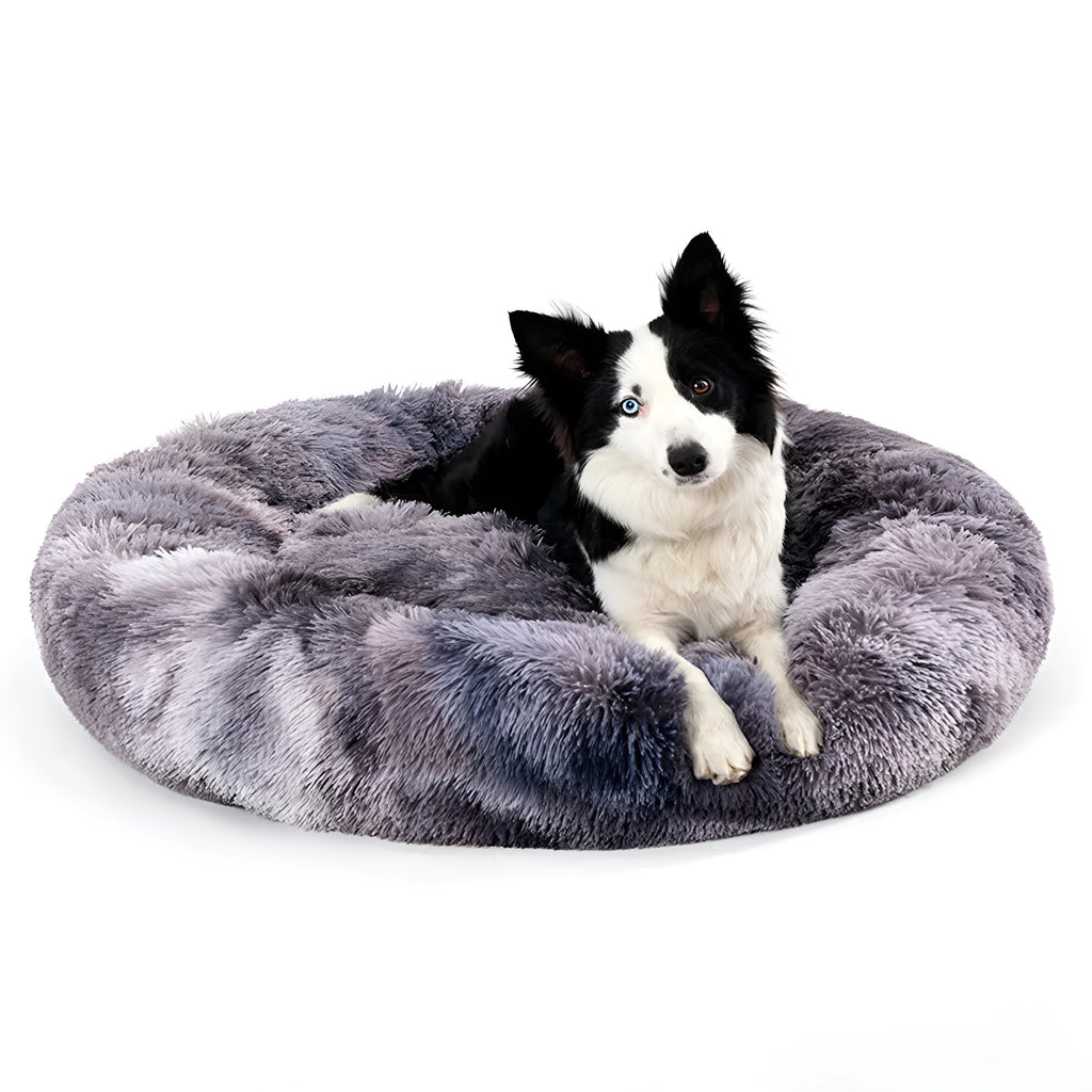 Fluffy donut-shaped dog bed in long plush material, shown in a grey colour, with a raised rim.