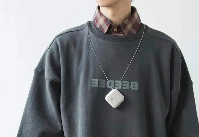 Mini USB air purifier pendant on a necklace, shown in pink colour with charging cable.
