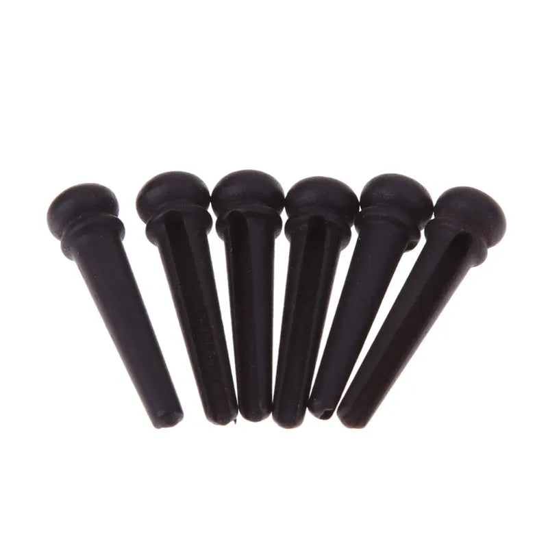 Six ebony guitar bridge pins with matt black finish on dark surface