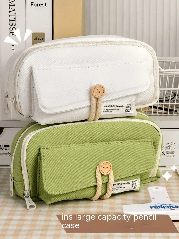 Canvas button-closure pencil case in beige, shown open with pens inside, demonstrating its large capacity.