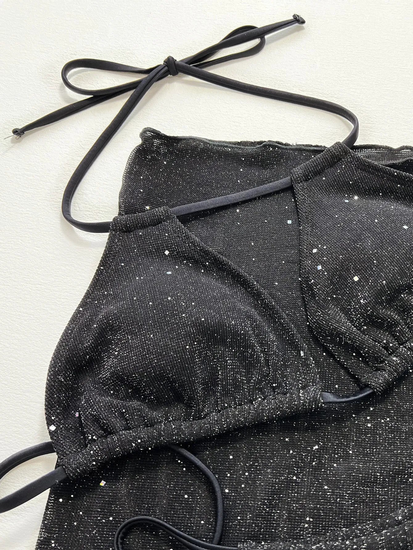 Black three-piece polyester bikini set with top and shorts on a size chart showing S, M, L.