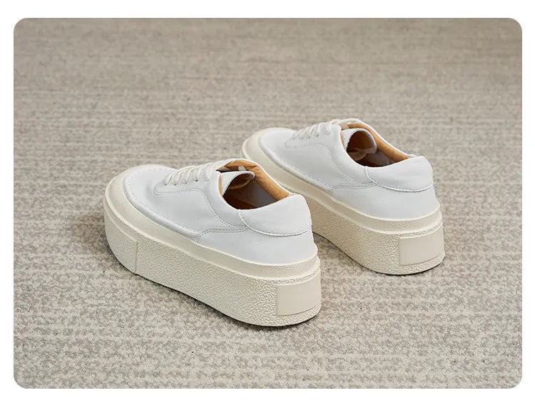 Black and white women's embossed leather platform sports shoes with a round toe and rubber sole.