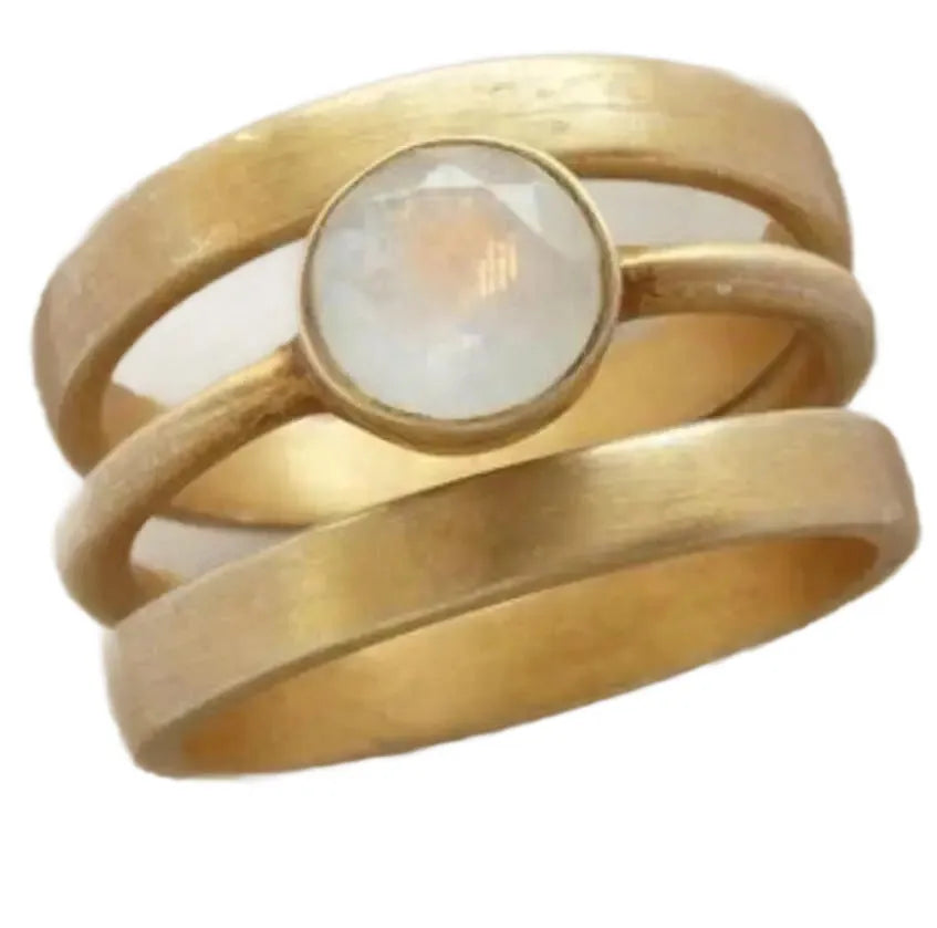 Gold geometric ring with linear detail and a small white chalcedony stone inlaid on a titanium steel band.