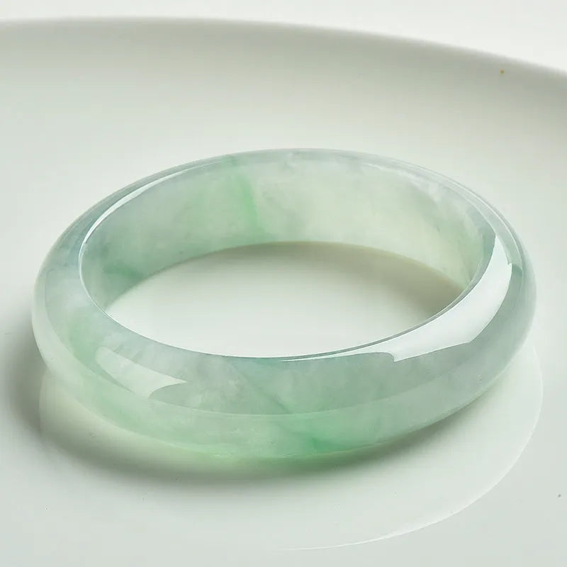 Natural light green jade bracelet on a wrist, showing unisex design and stone detail.