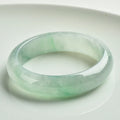 Natural light green jade bracelet on a wrist, showing unisex design and stone detail.