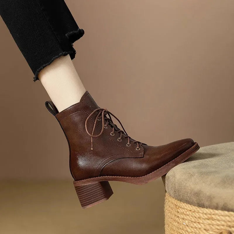 Women's black pointed-toe ankle boots with a short tube and block heel on a plain background