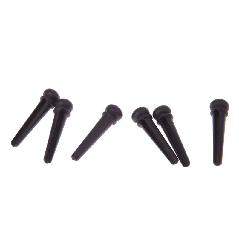Six ebony guitar bridge pins with matt black finish on dark surface