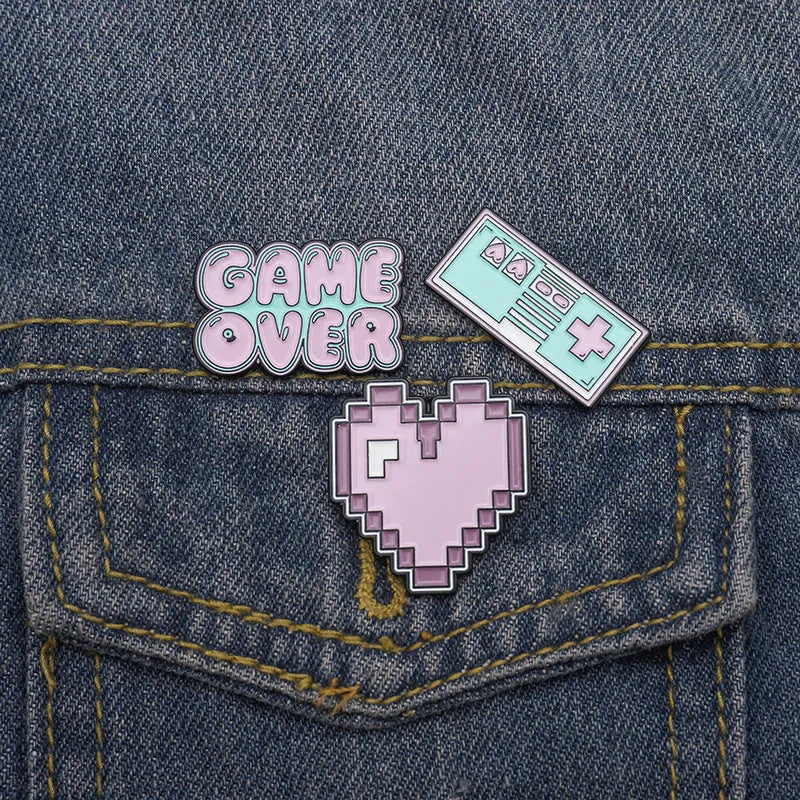 Stereo game console badge pin made from alloy metal on a bag, showing three colour variant options.