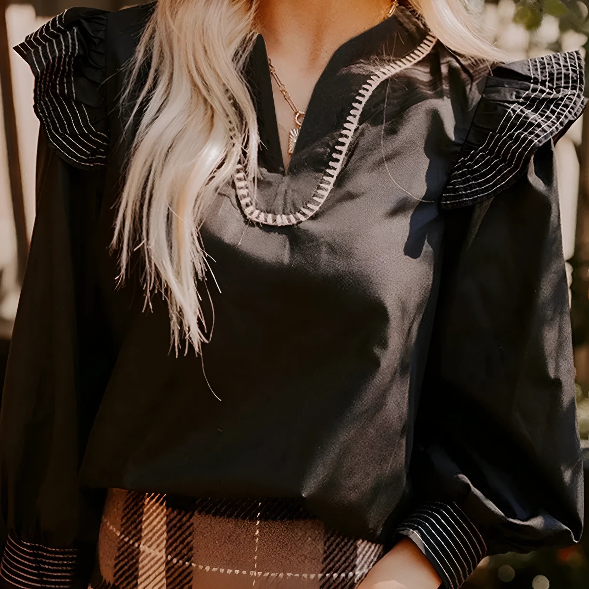 Black women's V-neck blouse with long ruffle sleeves and white contrast stitching.