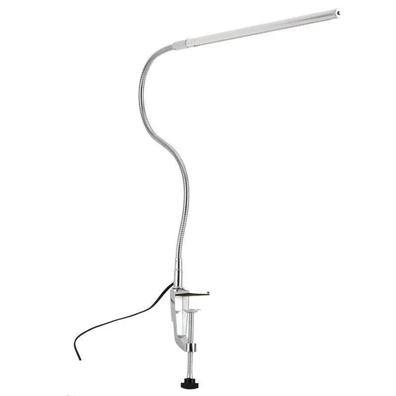 Silver long arm LED clip table lamp with USB cable, shown illuminating a nail art workspace.