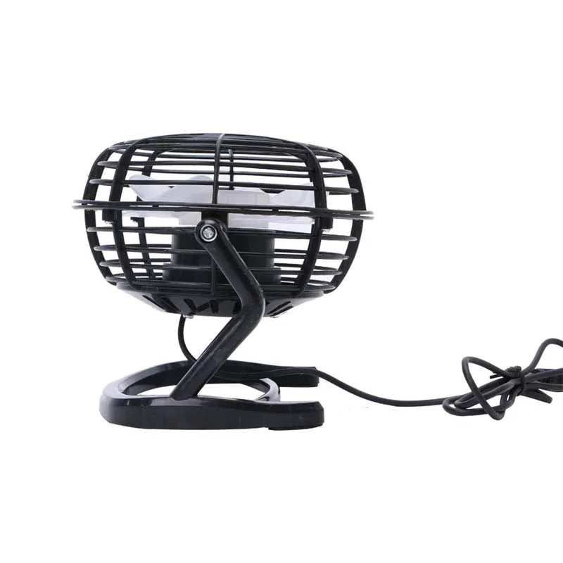 Mini black USB desk fan on a table next to a laptop, showing adjustable tilt angle.