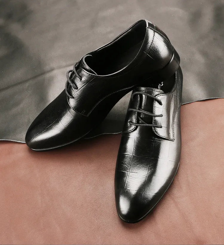 Men's black leather derby shoes with a pointed toe and rubber sole on a neutral background.