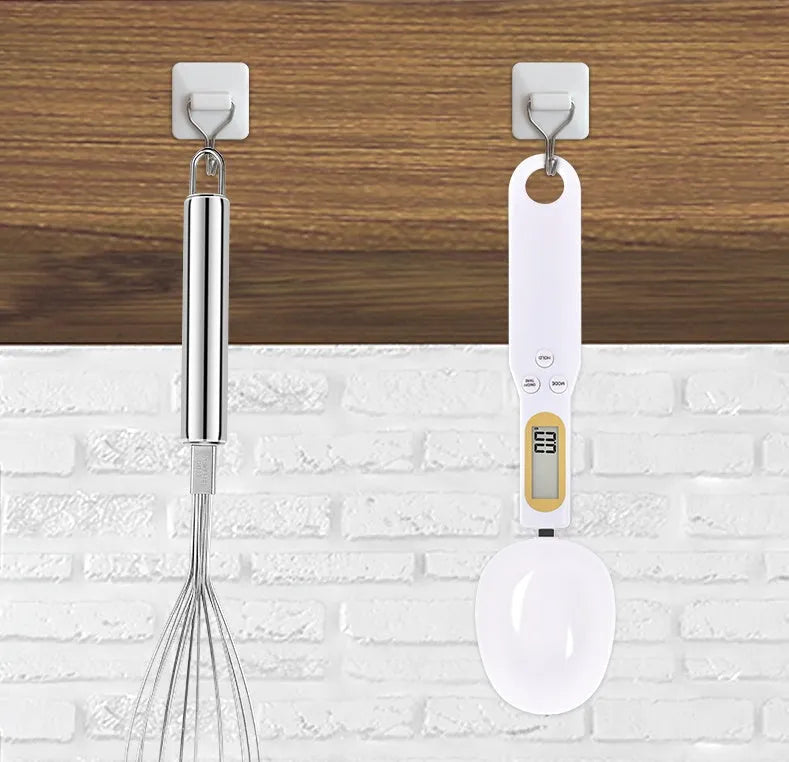 Black electronic measuring spoon scale showing digital display, placed on a kitchen counter.