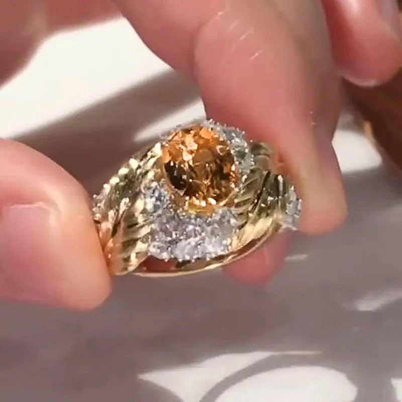 Gold-colour women's ring with a detailed embossed feather design and a central yellow zircon stone on a geometric copper band.