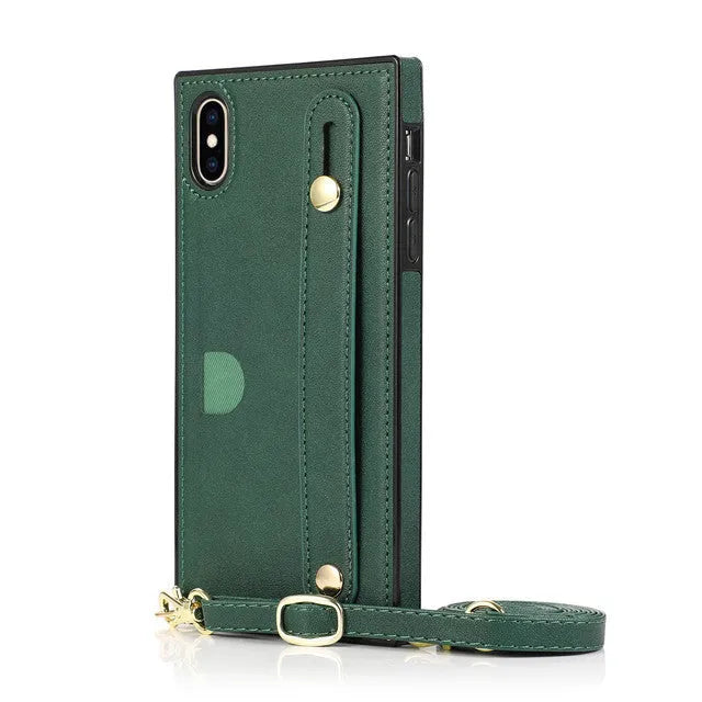 Black leather iPhone case with card holder slot and attached wrist strap on a table.