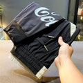 Men's solid black ultra-thin ice silk ankle-banded cropped casual trousers laid flat.