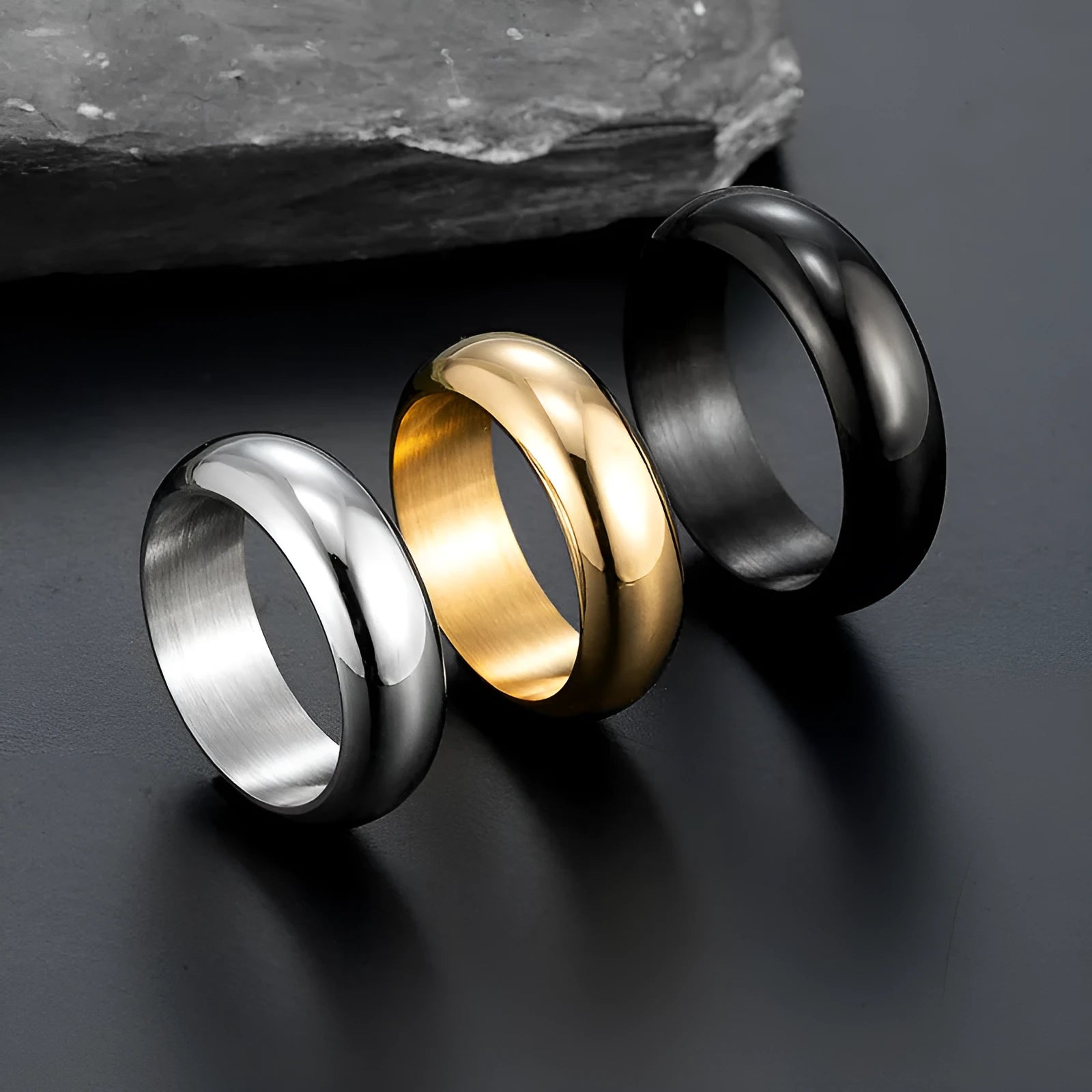 A glossy electroplated titanium steel ring shown in gold, black, and steel colour options on a plain background.