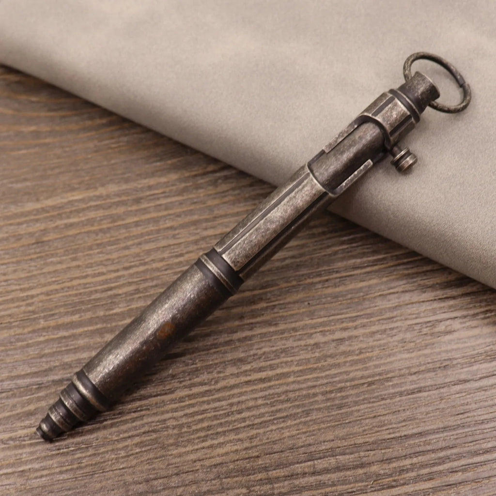 Retro brass tactical pen with a cylindrical barrel and bolt action mechanism on a dark background.