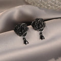 A pair of black rose zircon floral stud earrings with an 18K gold electroplated finish on copper.