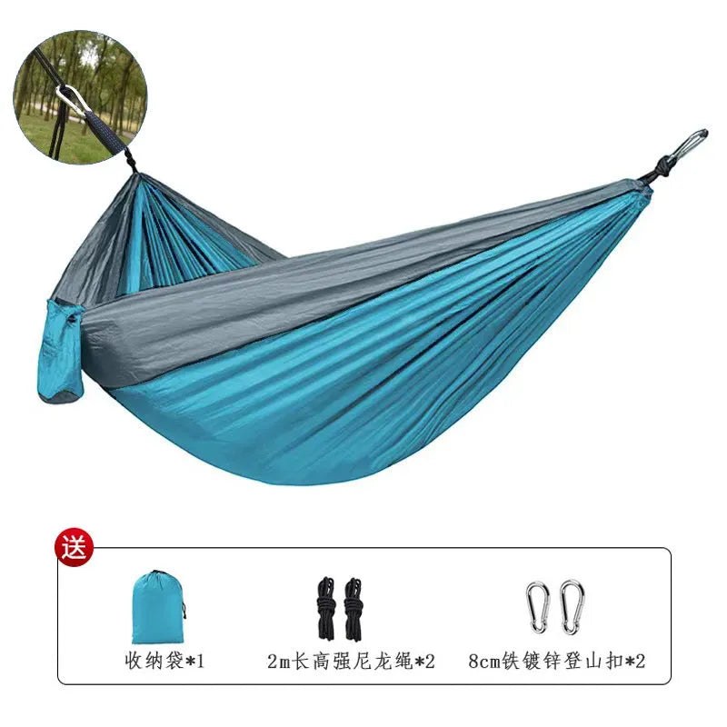 Large blue outdoor hammock made from parachute nylon fabric hanging between trees