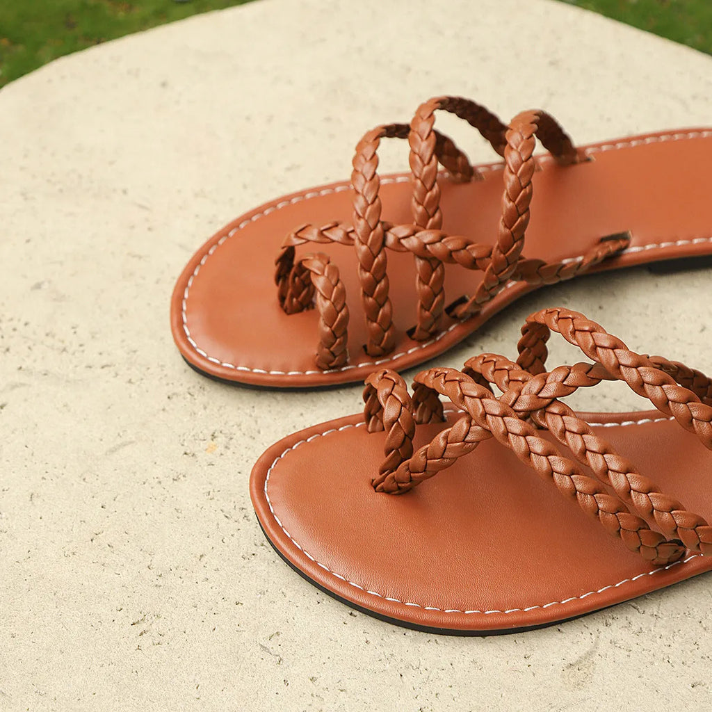 Womens woven clip-toe Roman sandals in black, brown, or white with a flat rubber sole.