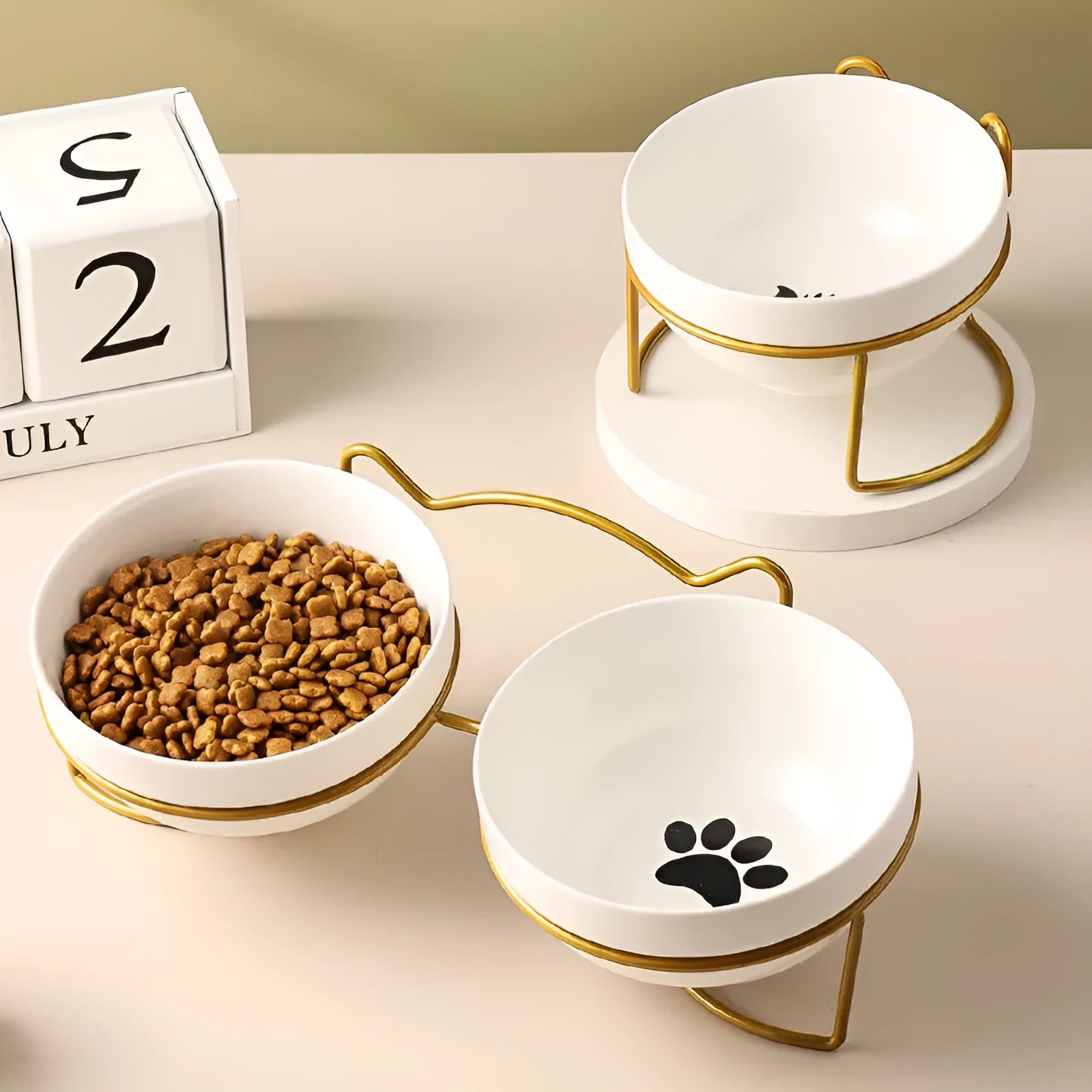 White ceramic cat bowl with cat paw print in a black iron frame stand with cat ears.
