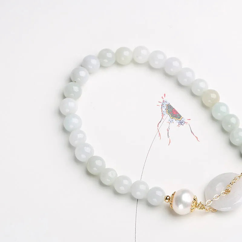 Green jade peace buckle charm and pearl beaded bracelet for women on a white background.